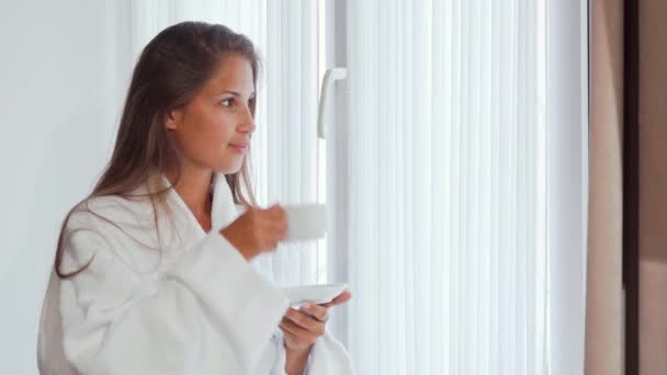 Junge Frau genießt ihren Morgenkaffee am Fenster — Stockvideo