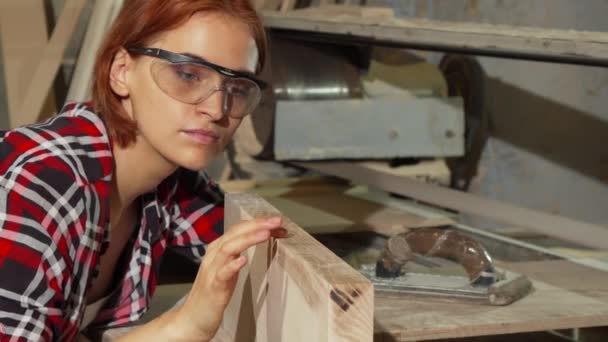 Vrouwelijke timmerman behandeling van houten plank na het schuren — Stockvideo