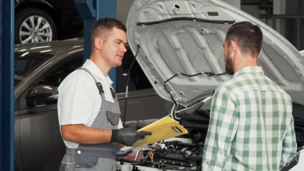 Otomotiv Servis Merkezi istemciye konuşurken araba tamircisi — Stok video