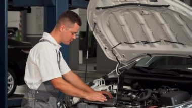 Arabayı tamir ederken dizüstü kullanarak profesyonel araba tamircisi