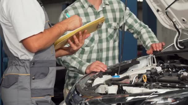 Mecánica de llenado de papeles mientras habla con el propietario del coche — Vídeo de stock
