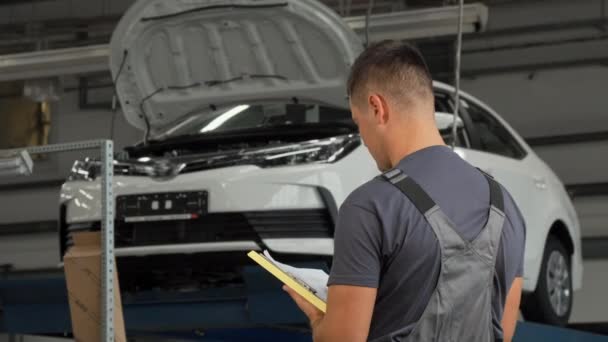 Zadní pohled na snímek auto mechanik náplň papíry — Stock video