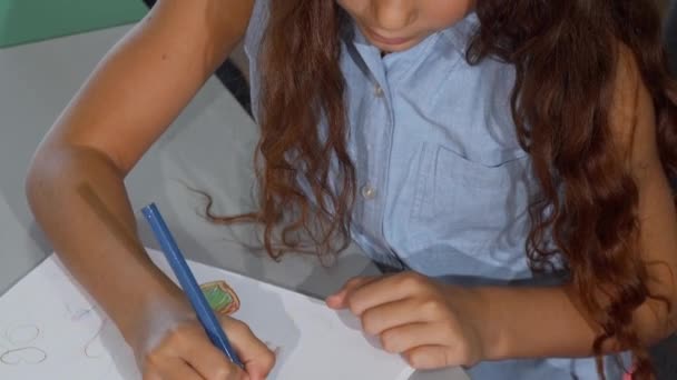 Linda niña pelirroja sonriendo alegremente, mientras dibuja — Vídeo de stock