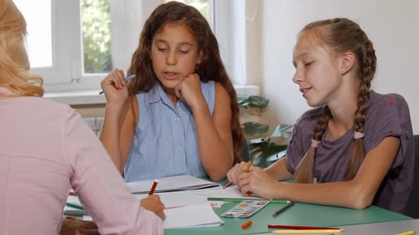 Two schoolgirls enjoying their art class with teacher at school — Stock Video