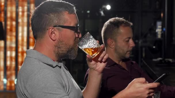 Glücklicher Mann lacht, während er Whiskey und Nachrichten auf seinem Smartphone trinkt — Stockvideo