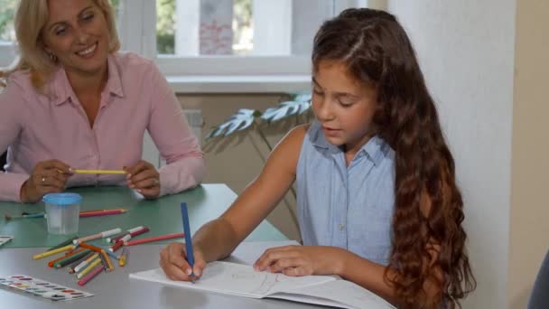 Schattig meisje terwijl haar vrolijke leraar kijken naar haar tekening — Stockvideo