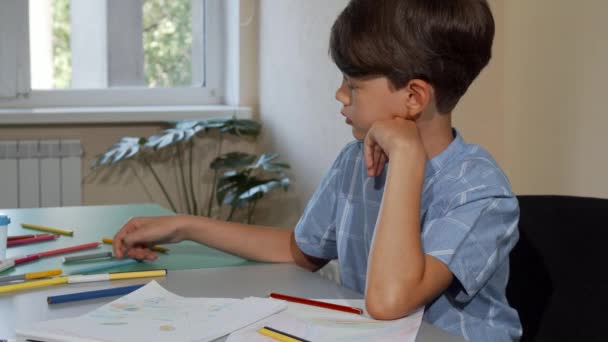 Jonge schooljongen op zoek vervelen terwijl kleuren zijn schetsboek — Stockvideo