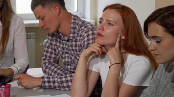 Rothaarige Frau sieht genervt aus, während sie in der Schule an einem Projekt arbeitet — Stockvideo