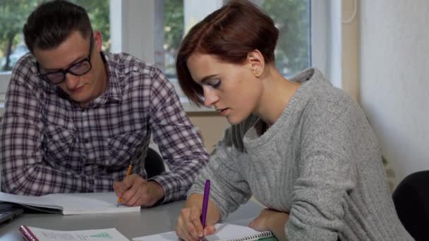 Estudantes escrevendo em seus livros didáticos na sala de aula — Vídeo de Stock