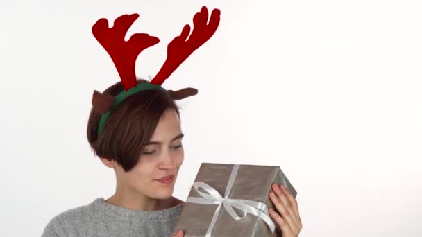 Ευτυχισμένη γυναίκα στο στήριγμα κεφαλής κέρατα ταράνδων βλέπουν την χριστουγεννιάτικο δώρο — Αρχείο Βίντεο