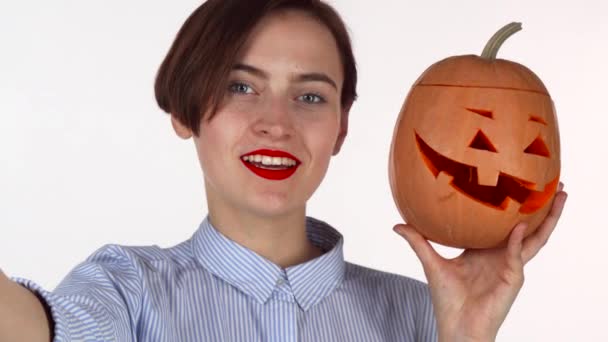 Linda mulher de lábios vermelhos tomando selfies com abóbora de Halloween esculpida — Vídeo de Stock