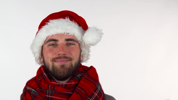 Schöner bärtiger Mann mit Weihnachtsmütze, der lächelnd ein Geschenk hochhält — Stockvideo