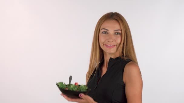 Hermosa deportista sosteniendo un tazón de ensalada, sonriendo a la cámara — Vídeo de stock