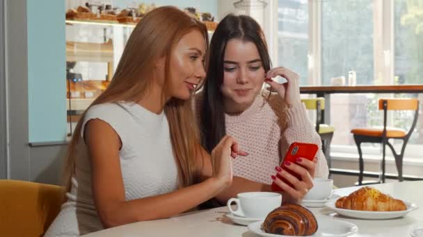 Femmes gaies attrayantes riant à la caméra, en utilisant le téléphone intelligent ensemble — Video