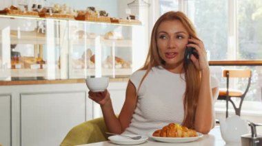 Kahve yaparken telefonda konuşurken heyecanlı, arayan genç kadın