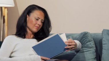 Rahat Olgun kadın evde kanepede kitap okuma keyfi