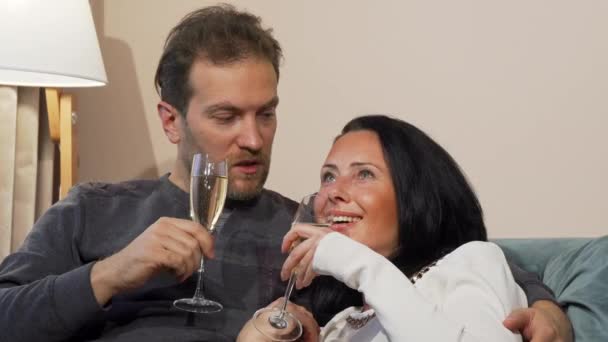 Happy mature couple laughing, drinking champagne while cuddling at home — Stock Video