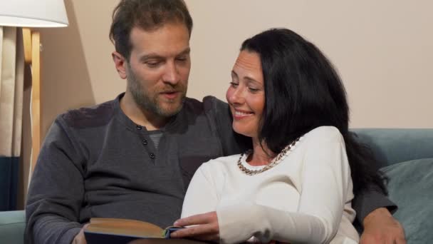 Прекрасна подружня зріла пара сміється, читаючи книгу разом — стокове відео