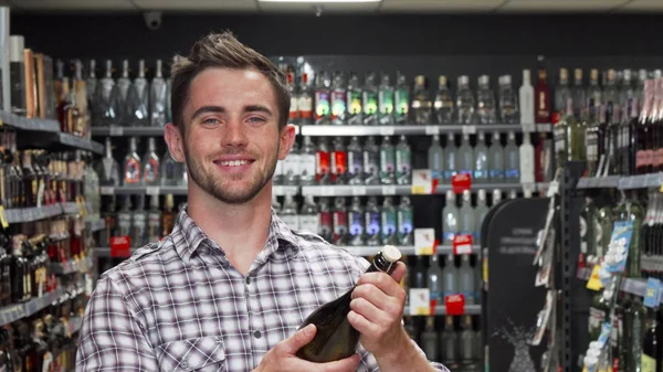 Şarap seçerken kameraya gülümseyen yakışıklı genç