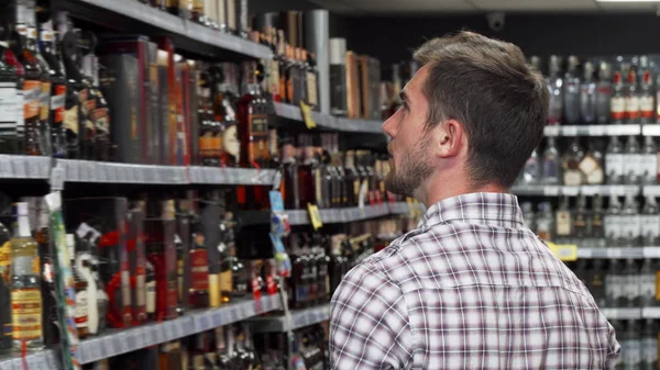 Dikiz kadeh şarap süpermarkette raflarda inceleyerek bir adam