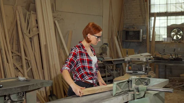 Vrouwelijke timmerman met machtshulpmiddelen tijdens haar workshop — Stockfoto