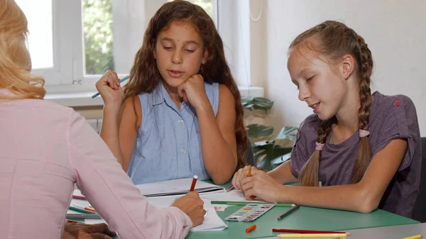 Dos colegialas disfrutando de su clase de arte con el profesor en la escuela —  Fotos de Stock