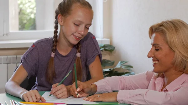 Gelukkig volwassen vrouwelijke leraar tekenen met haar student op school — Stockfoto