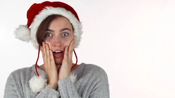 Jovem mulher bonita em chapéu de Natal olhando surpreso ou chocado — Fotografia de Stock
