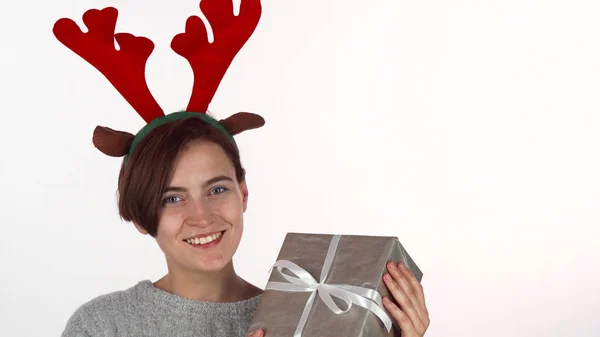 Счастливая женщина в оленьих рогах, смотрящая на свой рождественский подарок — стоковое фото