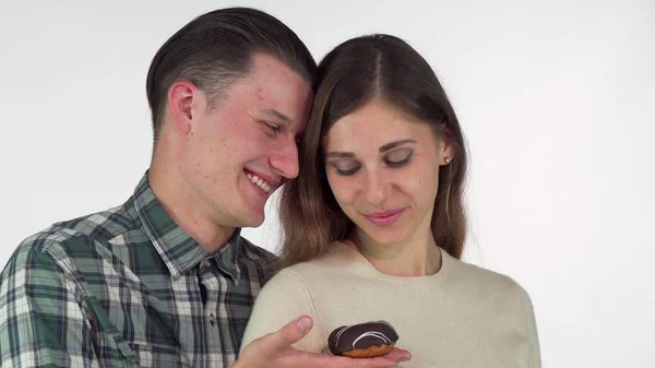 Joven sonriendo, ofreciendo donut de chocolate a su hermosa novia — Foto de Stock