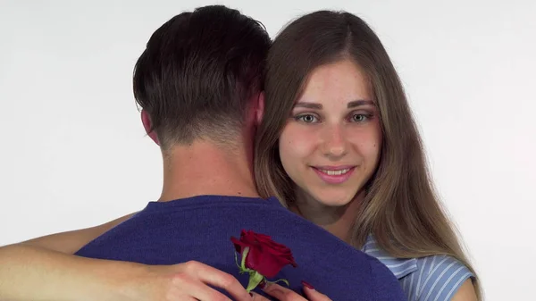 Mulher bonita sorrindo, segurando rosa vermelha enquanto abraça seu namorado — Fotografia de Stock