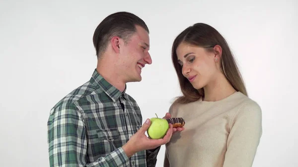 Красивый мужчина предлагает яблоко и пончик своей прекрасной девушке — стоковое фото