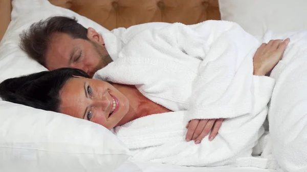 Mulher madura alegre vai dormir deitada na cama com o marido — Fotografia de Stock