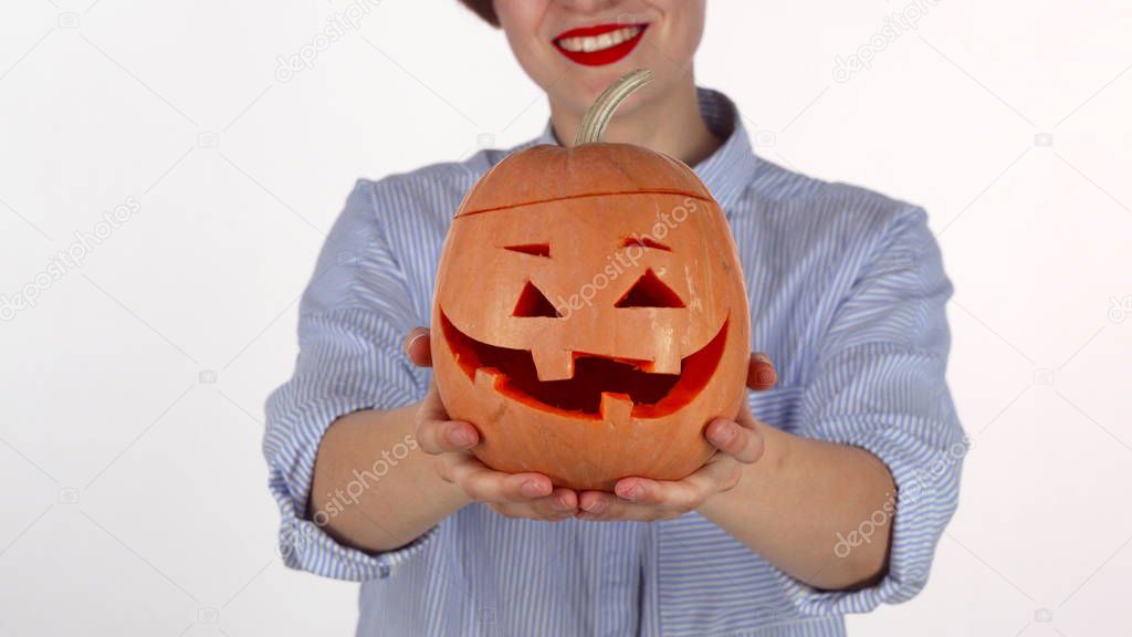 Red lipped woman holding out carved Halloween pumpkin to the camera
