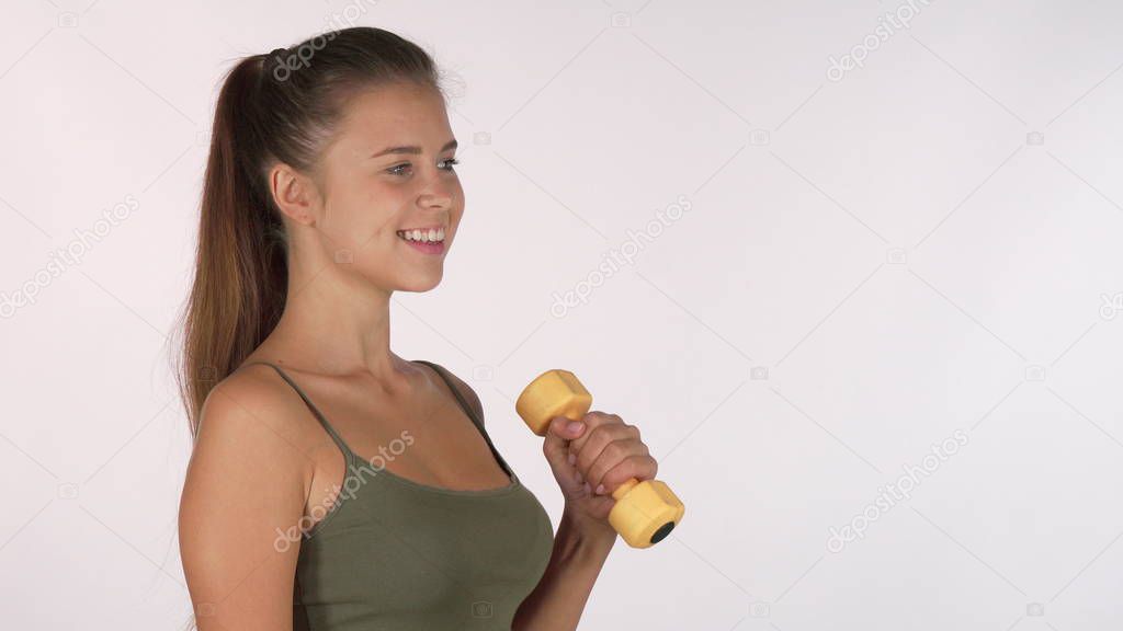 Happy sportswoman smiling to the camera while exercising with dumbbells