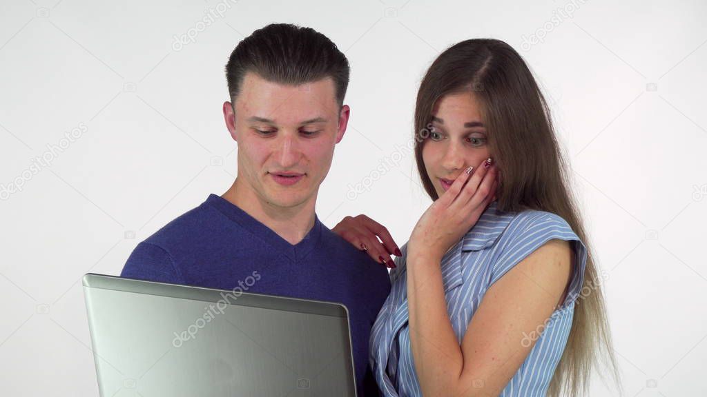 Young woman looking surprised while using laptop with her boyfriend