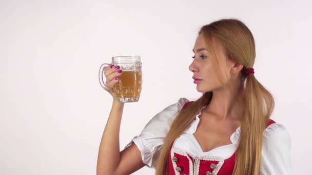 Сексуальная женщина с фестиваля Октоберфест тщательно рассматривает пиво в кружке — стоковое видео