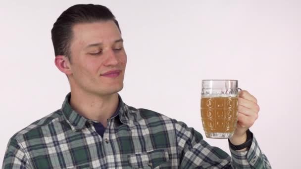 Счастливый молодой человек мечтательно смотрит в сторону, держа кружку вкусного пива — стоковое видео