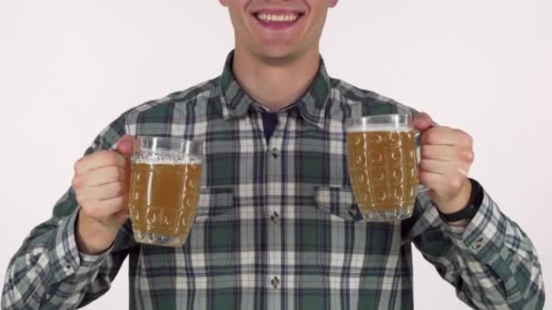 Feliz hombre sonriendo, sosteniendo dos tazas de cerveza a la cámara — Vídeo de stock