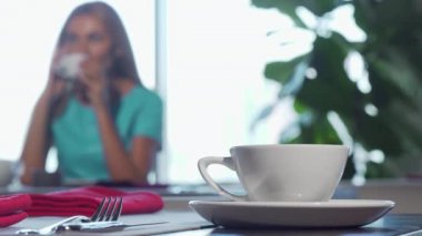 Cafe masa, kadın arka plan telefonda konuşurken bir bardakta üzerinde seçici odak