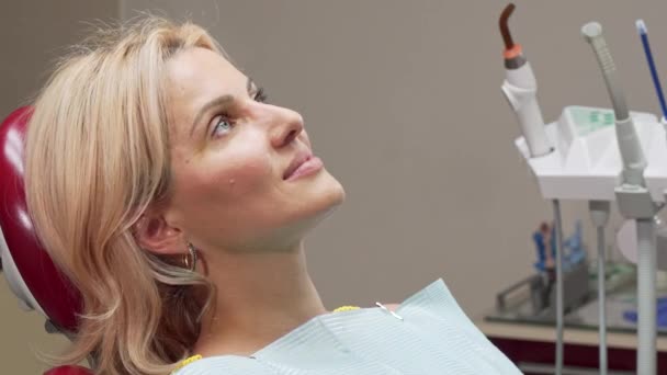 Красива зріла жінка посміхається радісно сидячи в стоматологічному кріслі — стокове відео