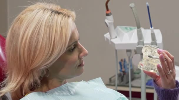 Mujer madura sonriendo a la cámara, sosteniendo el molde dental en la clínica — Vídeos de Stock