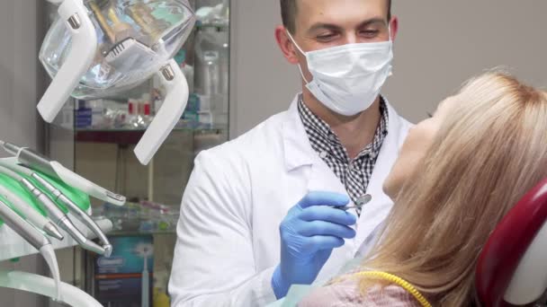 Dentista masculino usando máscara médica examinando dentes de paciente do sexo feminino — Vídeo de Stock