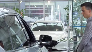 Galeride satın almak düşünceli çenesini ovuşturarak, yeni araba seçme genç adam