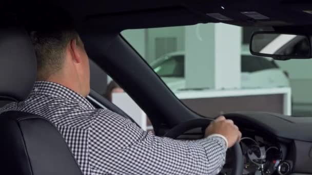 Jóképű férfi mosolyogva mutatja a válla fölött remek, ül egy új autó — Stock videók