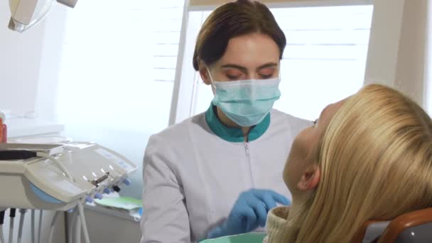 Dentista feminina trabalhando, examinando os dentes de uma paciente na clínica — Vídeo de Stock