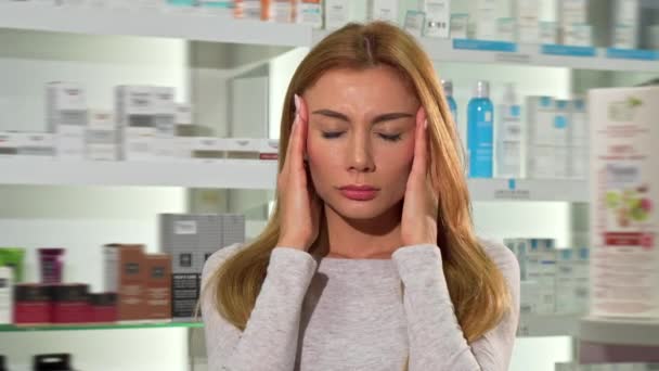 Прекрасная молодая женщина, страдающая головной болью в аптеке — стоковое видео