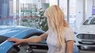 Çekici kadın yeni bir araba galerisinde eğilerek kameraya gülümseyen