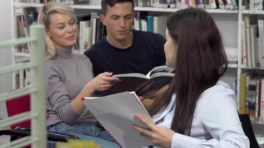 Genç kız öğrenci Kütüphanesi'nde arkadaşlarına konuşurken kameraya gülümseyen