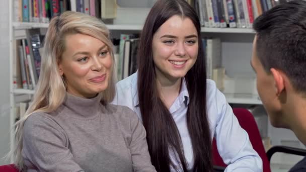 Belle ragazze del college ridendo, parlando con il loro compagno di classe presso la biblioteca del campus — Video Stock